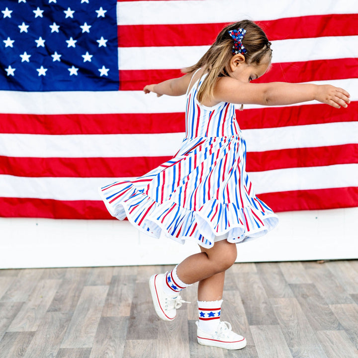 little girl twirling in red, white and blue striped 4th of july dress and cute star design socks