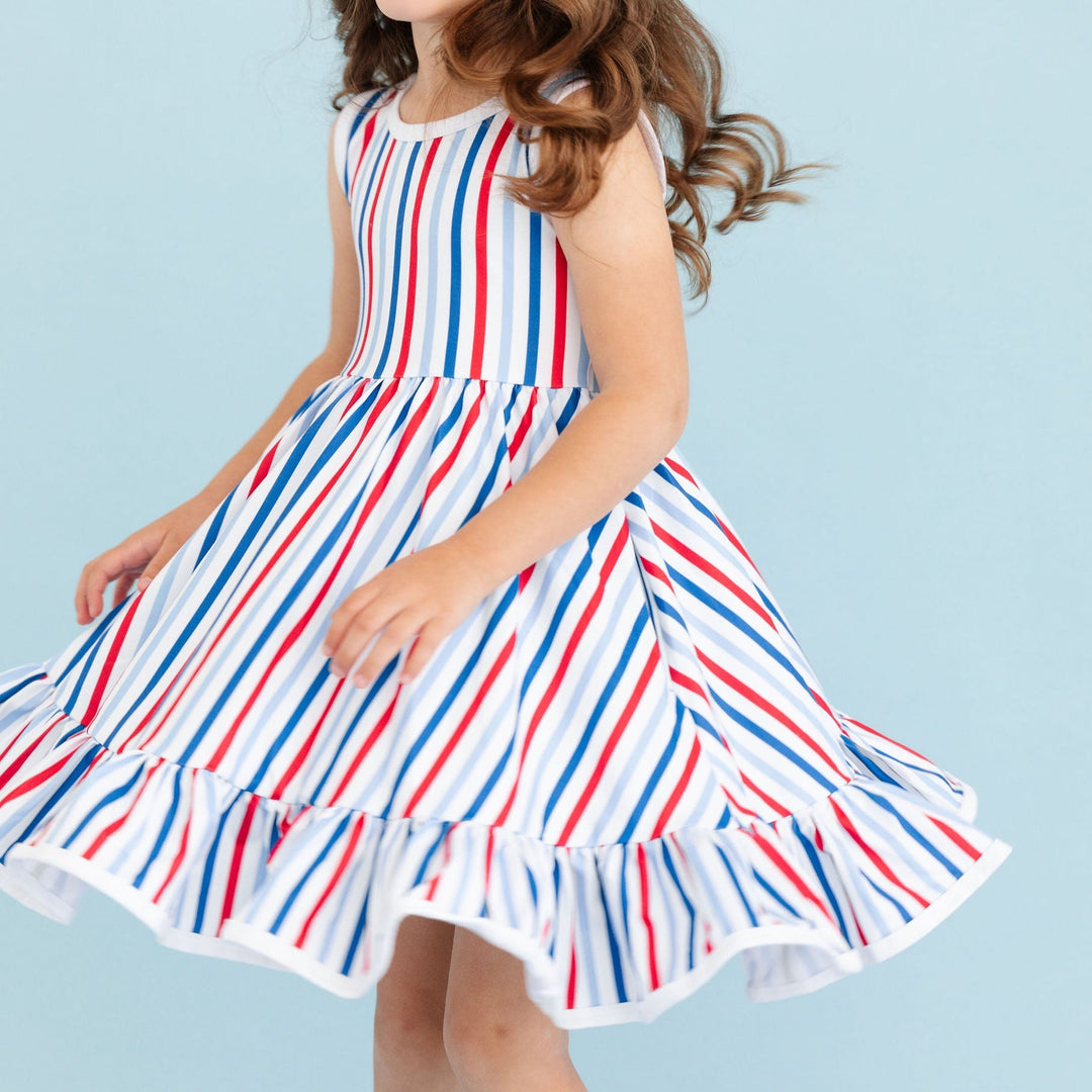 girl twirling in red, white and blue striped 4th of july dress
