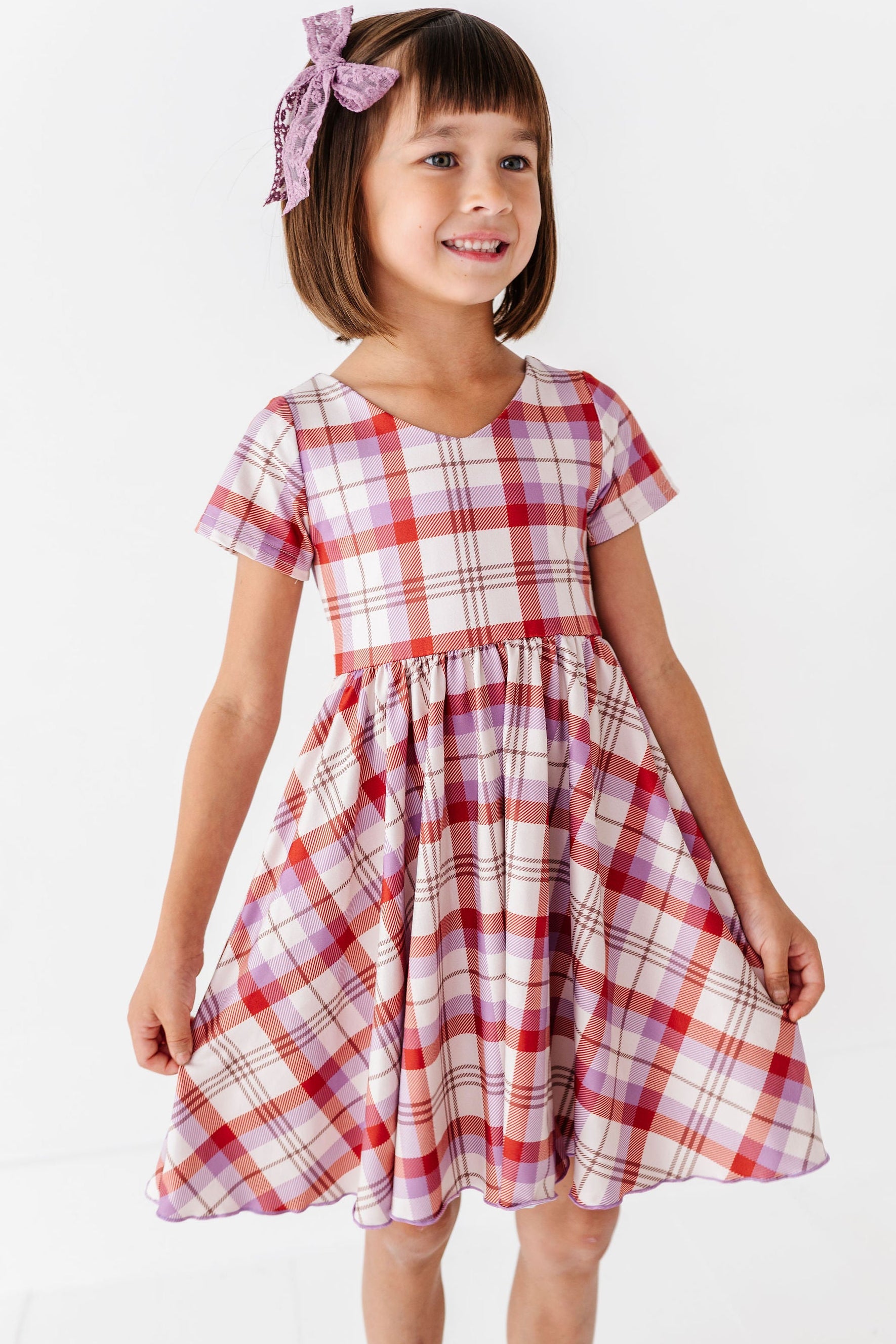girl wearing rust and purple plaid fall dress with matching purple lace hair bow
