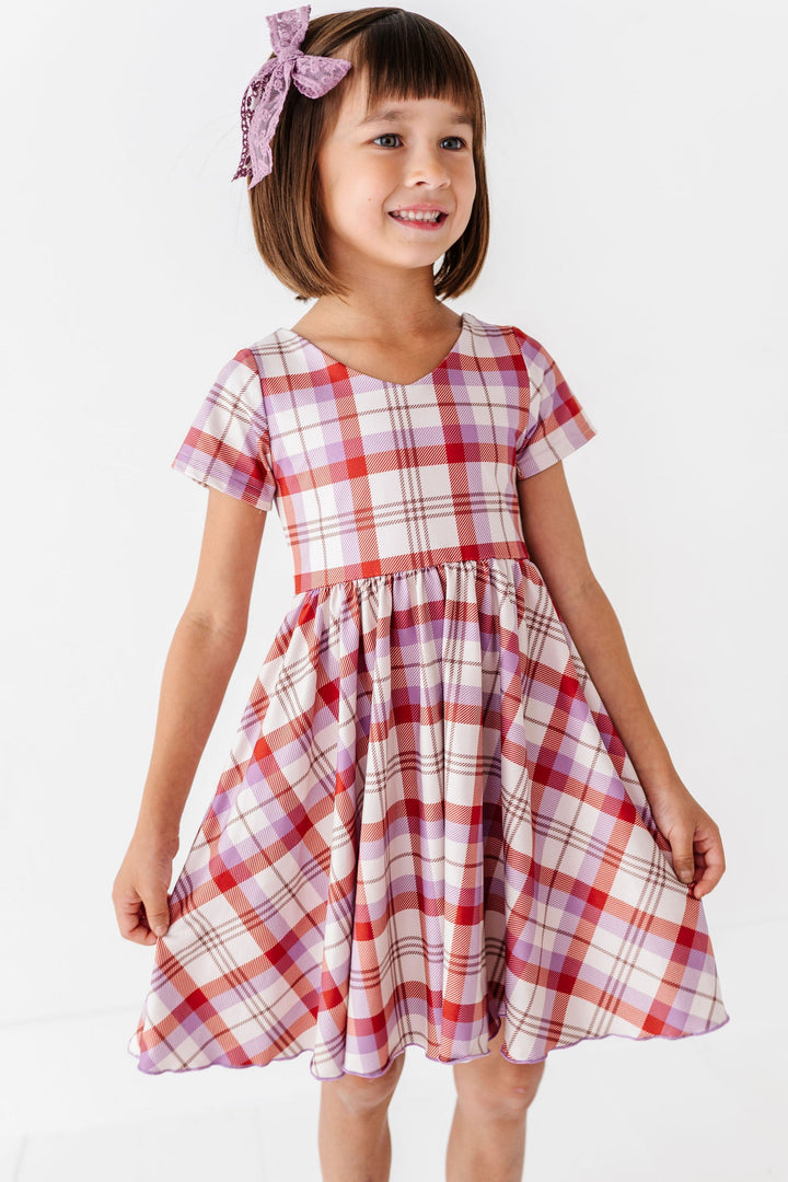 girl wearing rust and purple plaid fall dress with matching purple lace hair bow