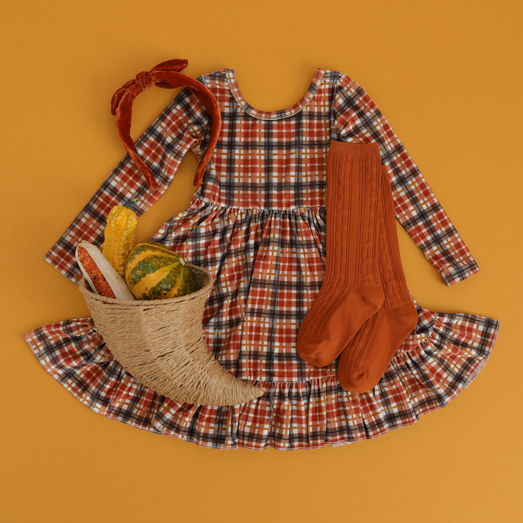 flatlay of fall velvet plaid dress with pumpkin orange cable knee highs and orange velvet headband