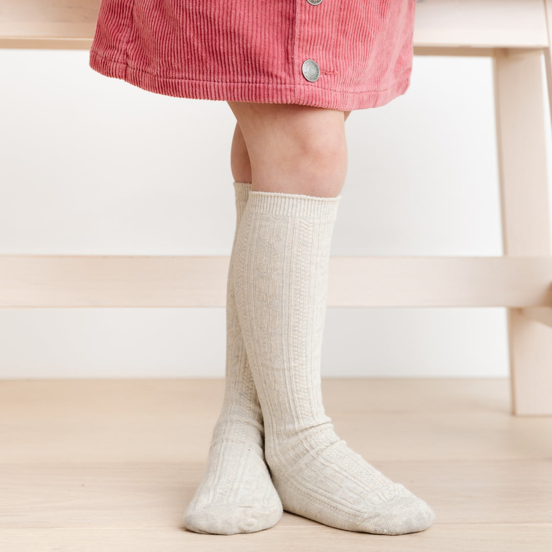 little girl wearing melange heathered ivory cable knit knee high socks