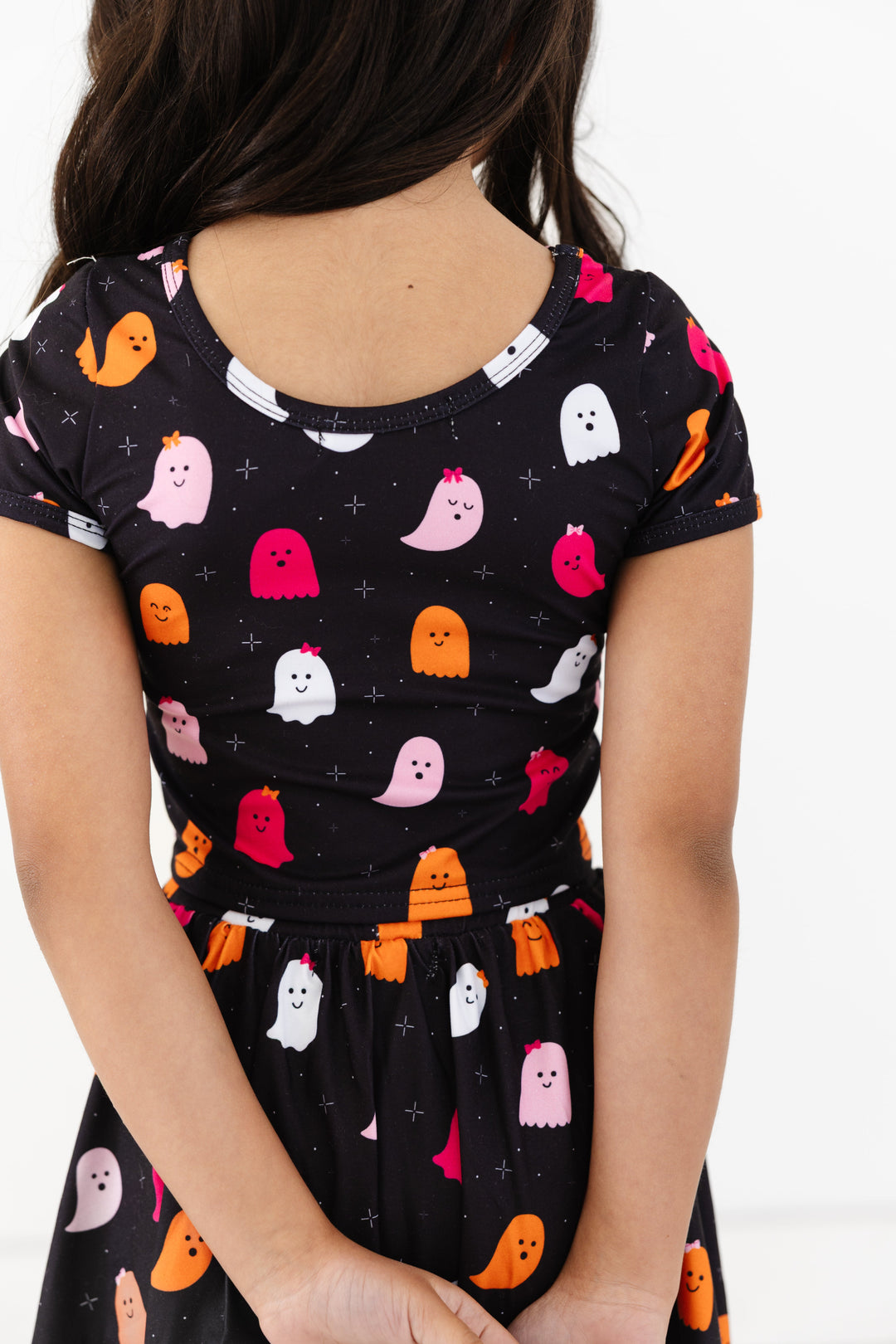 back view of little girl in scoop back fitted top in black with pink, orange and white ghost print made to match Halloween skort