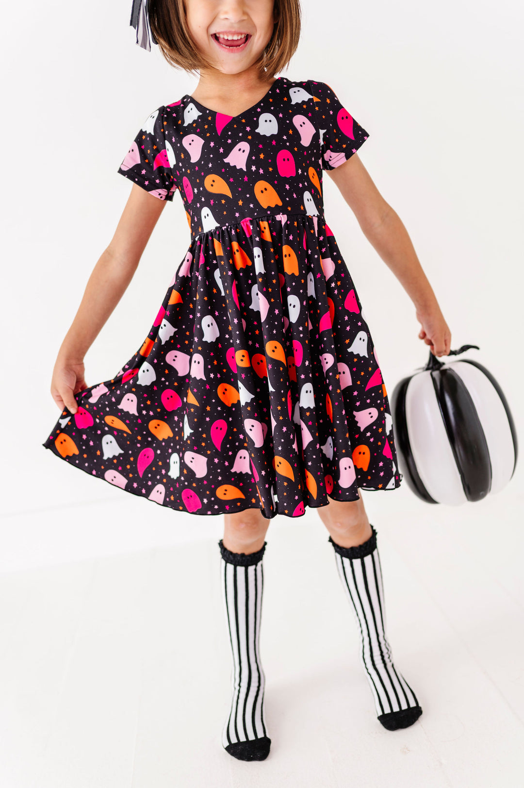 girl wearing ghost print halloween dress with black and white stripe knee high socks