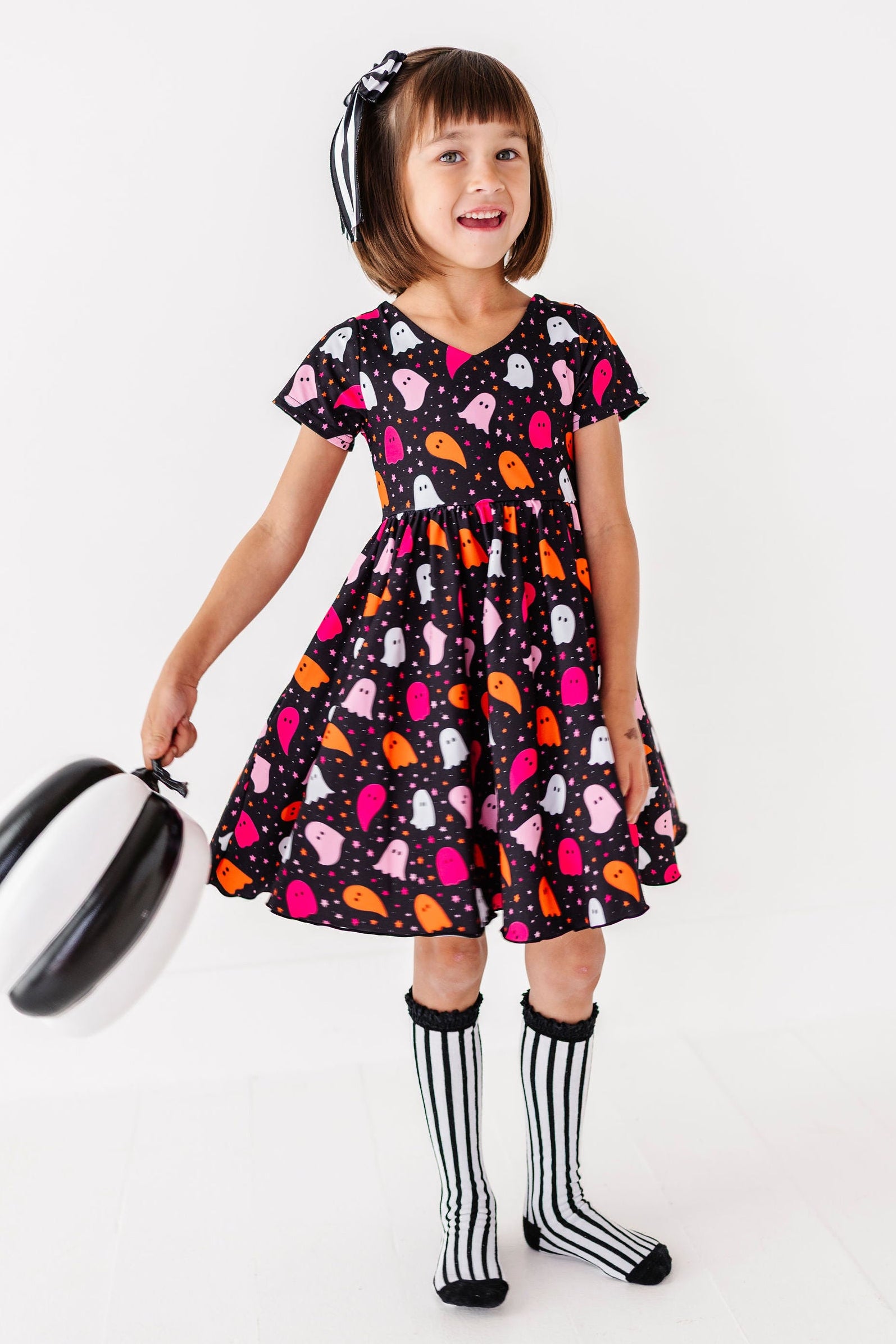 girl wearing black, pink and orange ghost print halloween dress