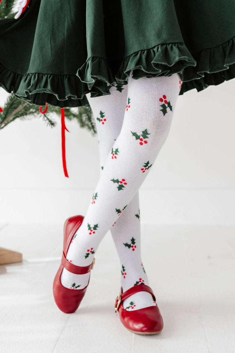 detail photo of girls legs wearing holly knit christmas tights with red t-strap shoes and forest green twirl dress