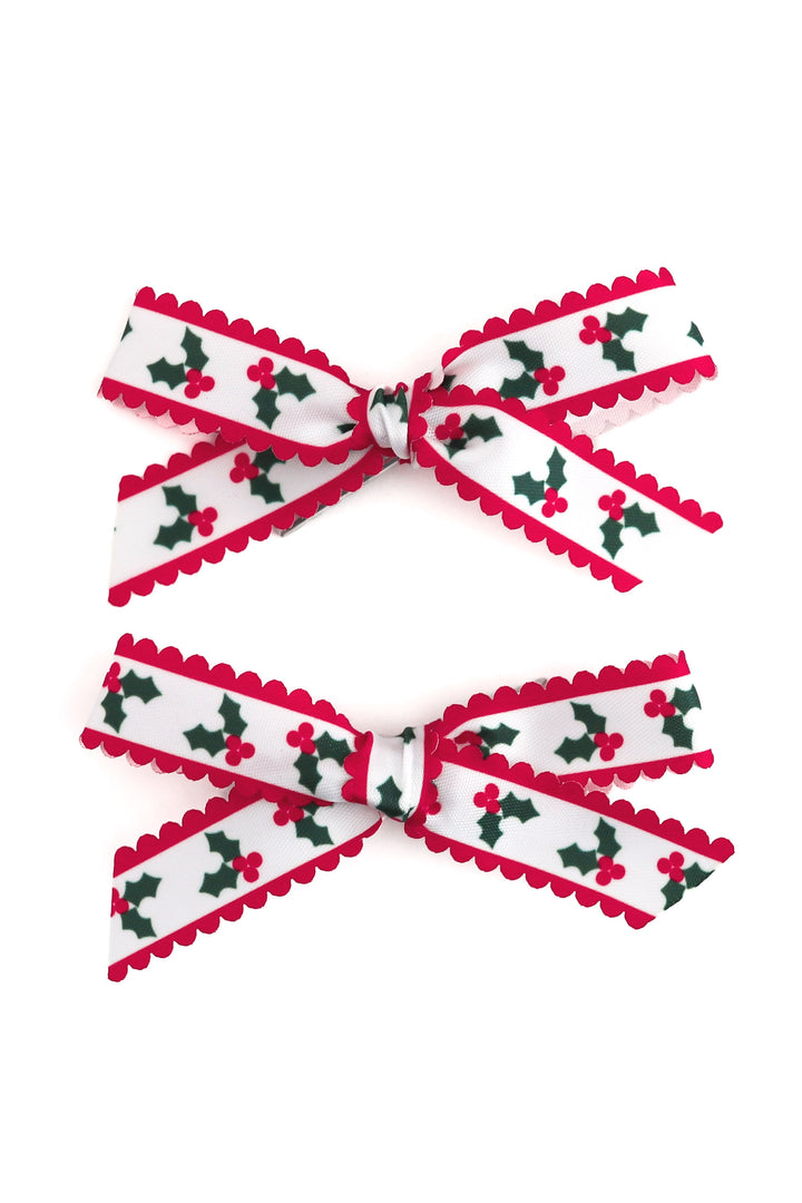 printed scallop ribbon pigtail bows on white ribbon with red and green holly deisgn with red scalloped edges shown on white background