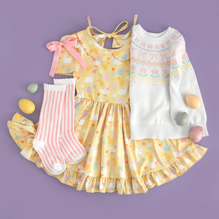 girls' styled Easter outfit featuring pastel yellow twirl dress with peter pan collar and novelty Easter print paired with white fair isle sweater with spring motif and matching pink and white knee high socks