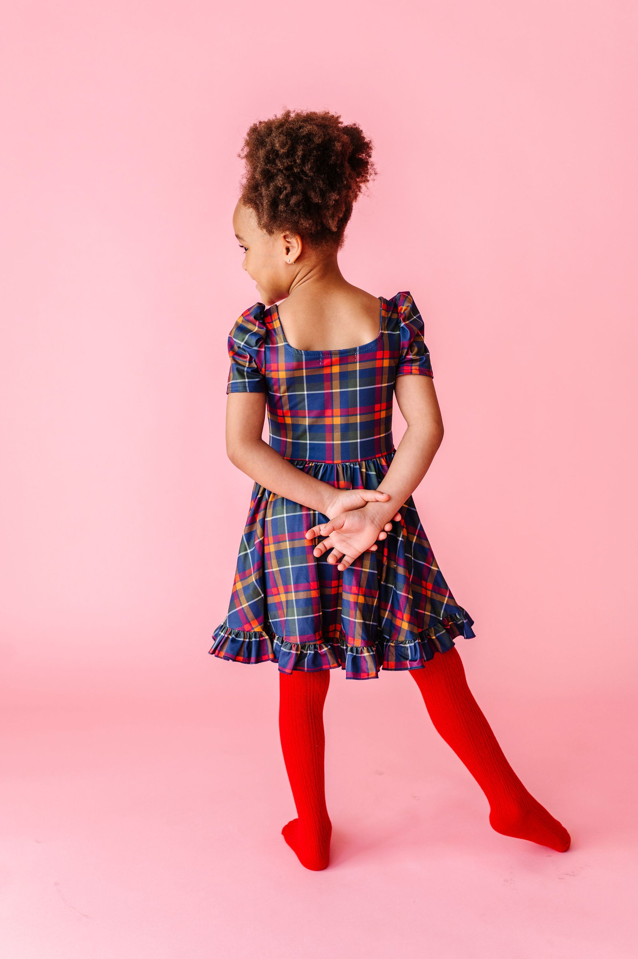 little girl wearing navy plaid dress with red cable knit tights