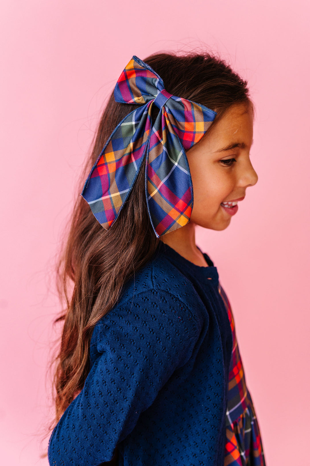Girl wearing back to school hair bow in navy plaid print