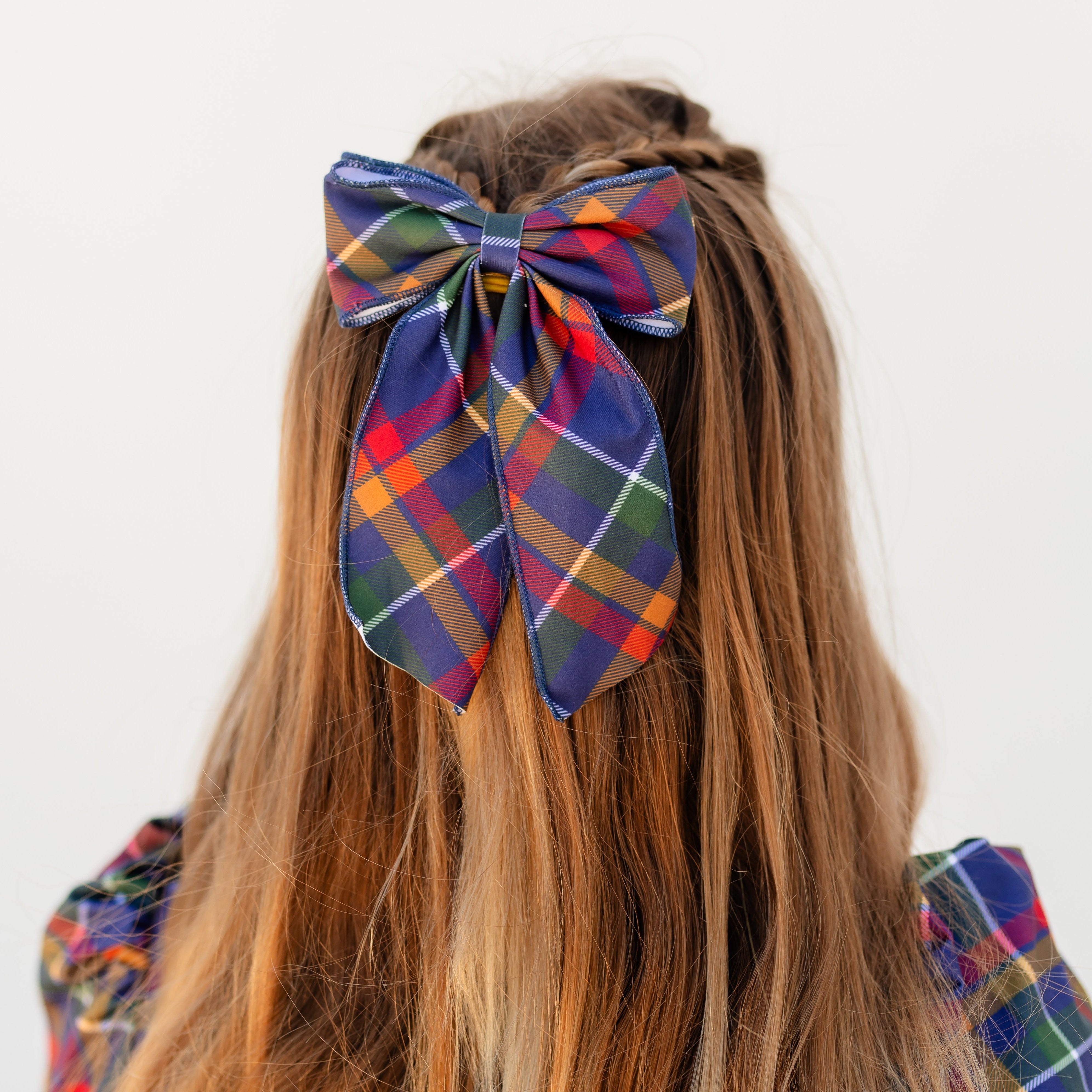 girl wearing oversized double fabric bow in navy plaid print with matching twirl dress for back to school