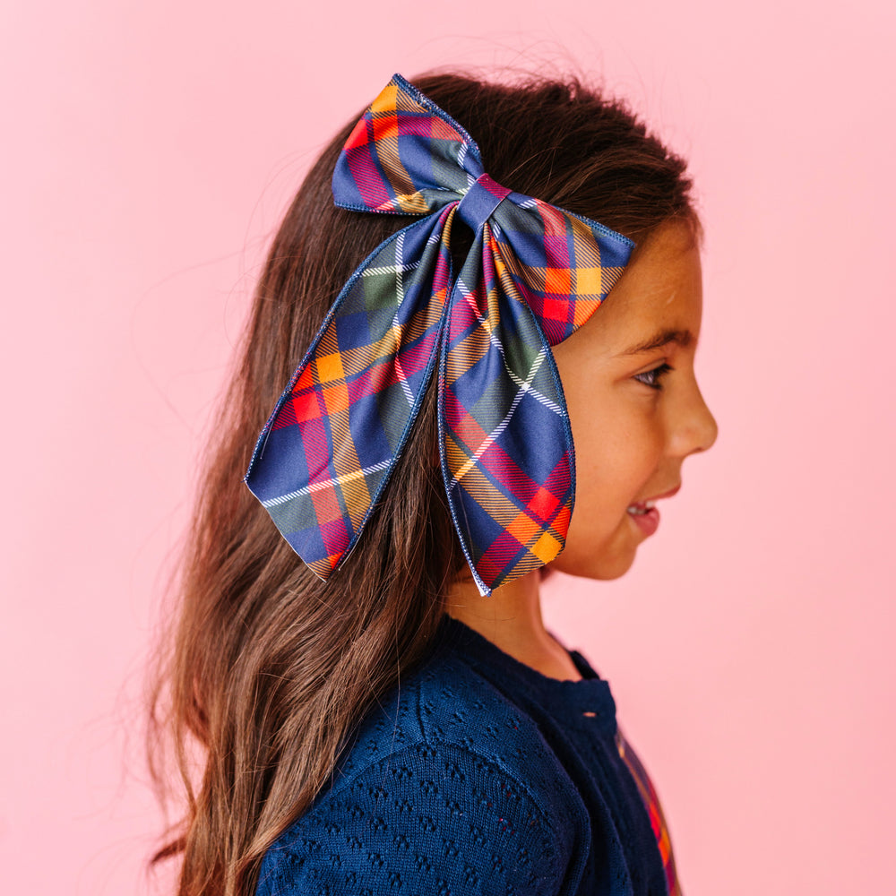 girl wearing navy plaid dress and matching fabric print bow on clip paired with pointelle navy blue cardigan