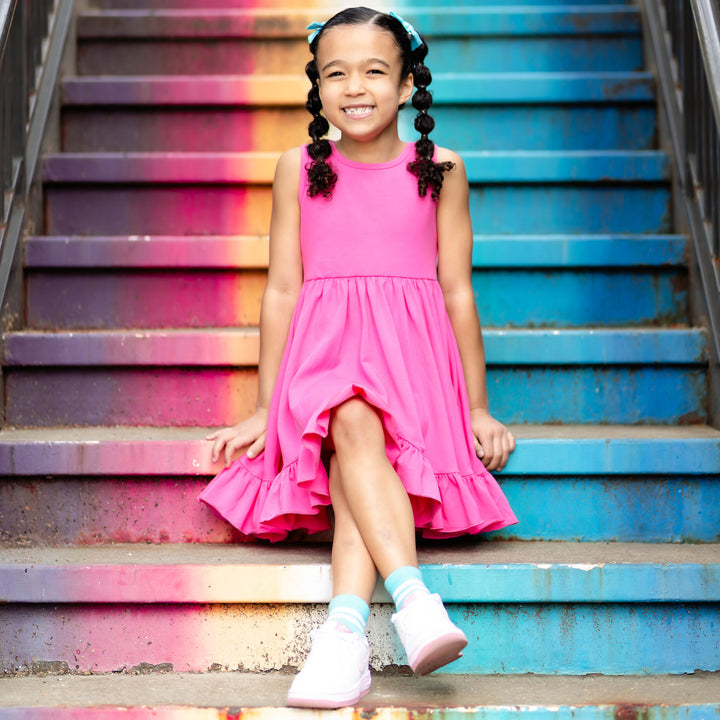 little girl sitting on rainbow steps in hot pink cotton summer dress