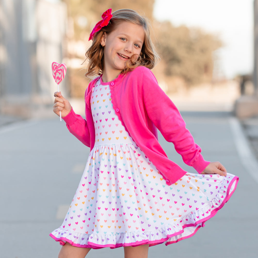 little girl in rainbow heart twirl dress and matching hot pink cardigan sweater