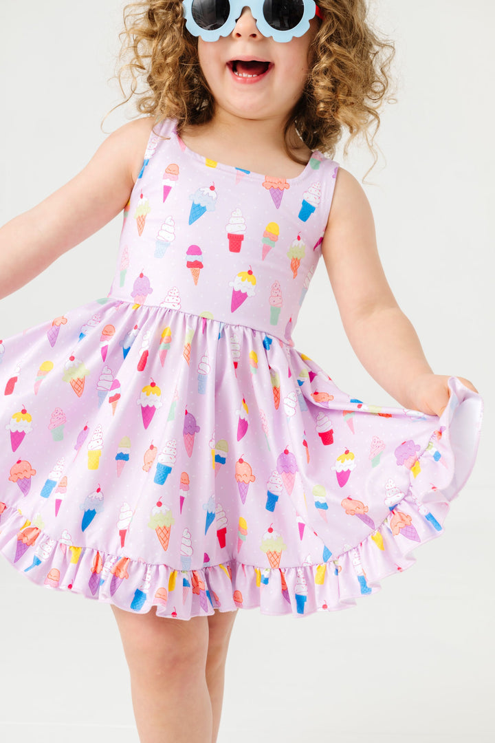 little girl in flower sunnies and sleeveless ice cream print twirl dress with square neckline and ruffle hem 
