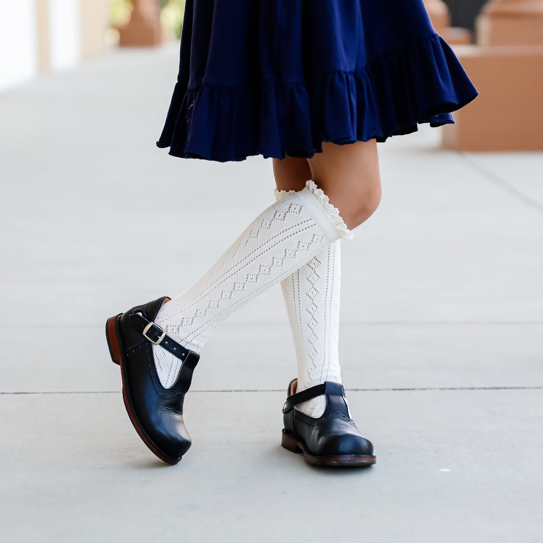 little girl in ivory crochet knit knee high socks wearing navy school uniform dress