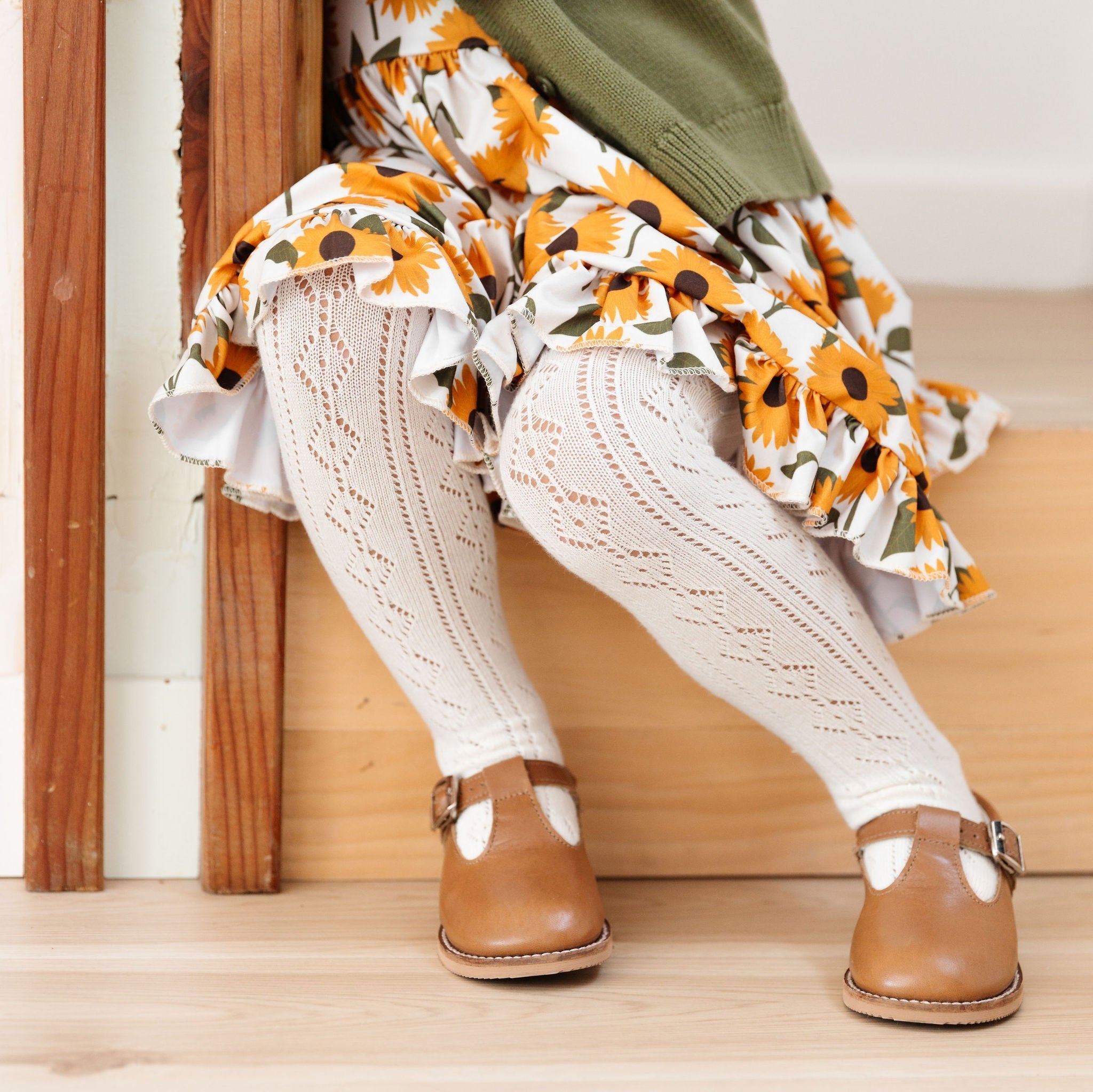 little girl in sunflower dress and matching ivory crochet knit tights