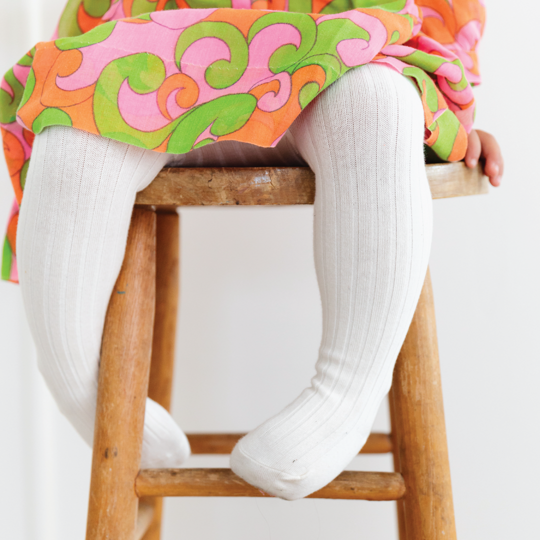 ivory ribbed cotton tights on toddler girl sitting on brown stool