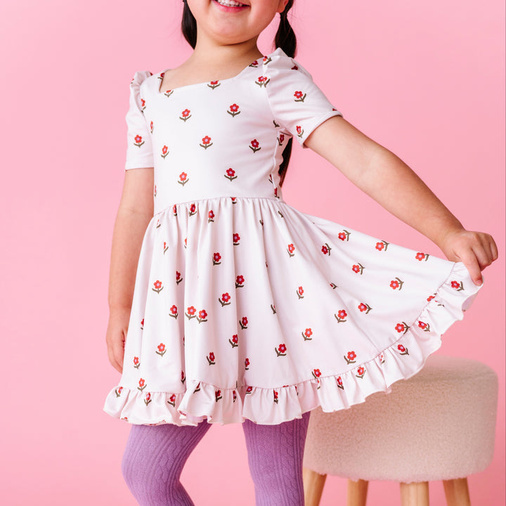 little girl posing in ivory square neck, short sleeve twirl dress with rust flower print paired with fall purple cable knit tights