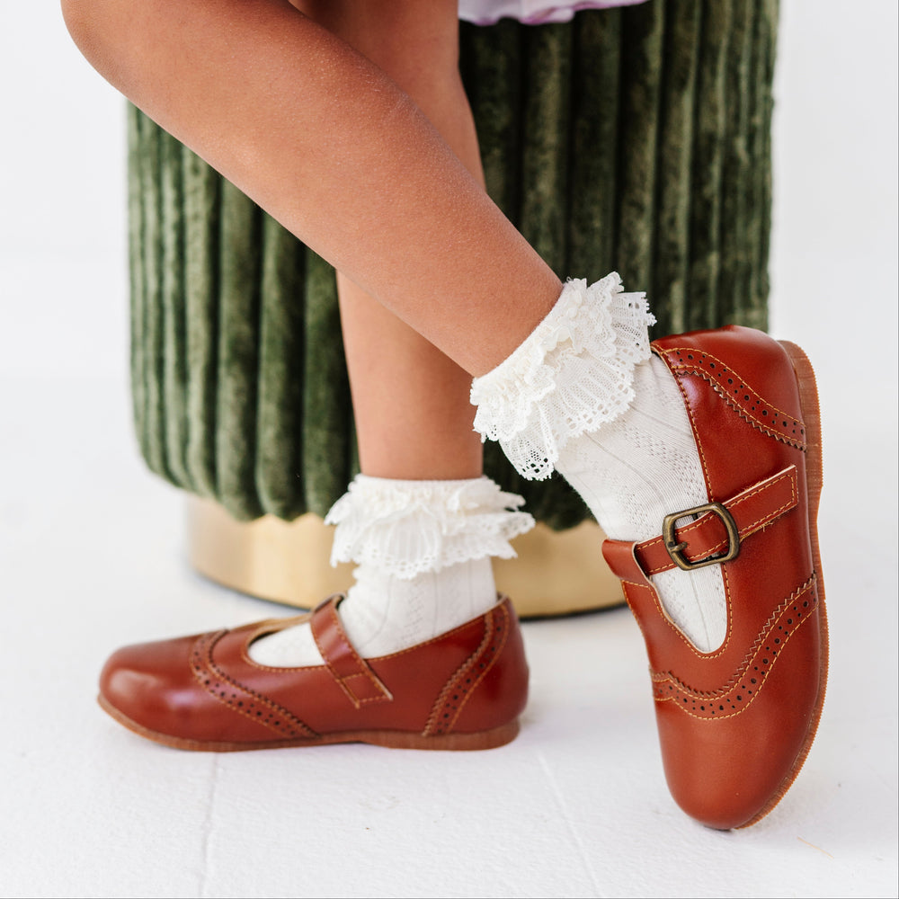 young girl wearing brown mary janes paired with ivory lace trim ankle socks