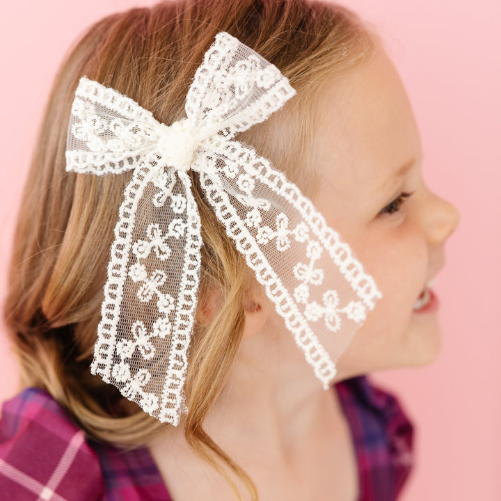 little girl in light cream lace bow on clip paired with purple plaid twirl dress for fall
