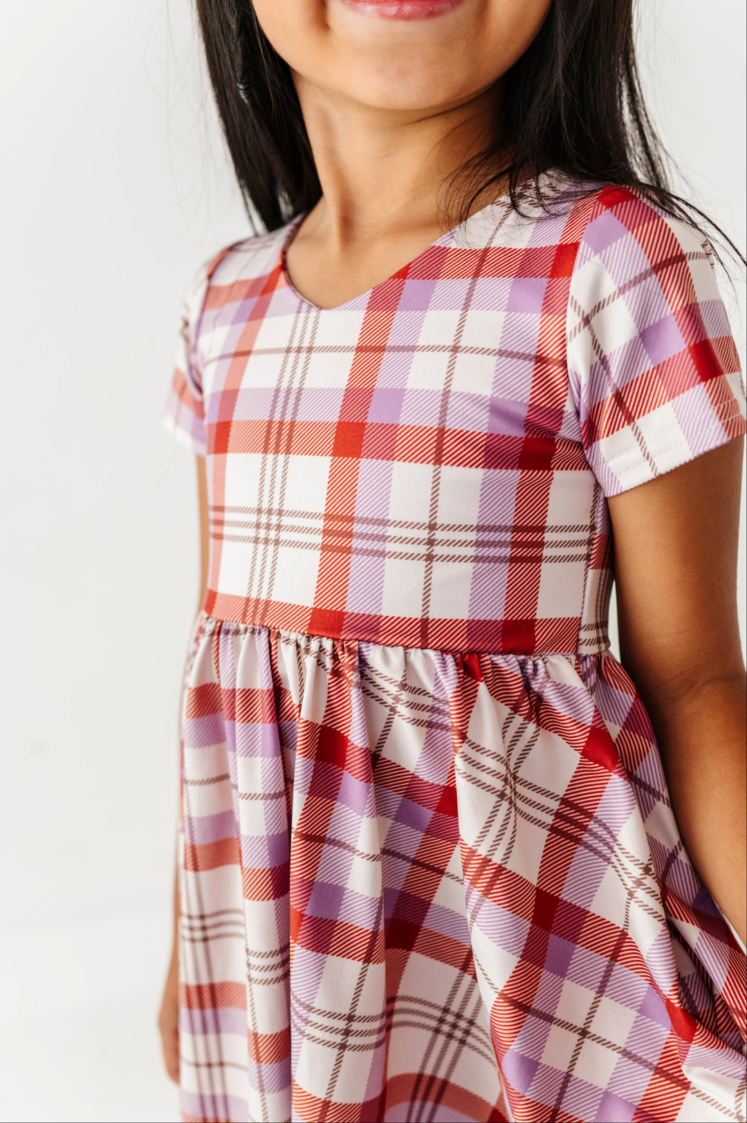 closeup of v-neck twirl dress bodice in ivory, rust and amethyst plaid
