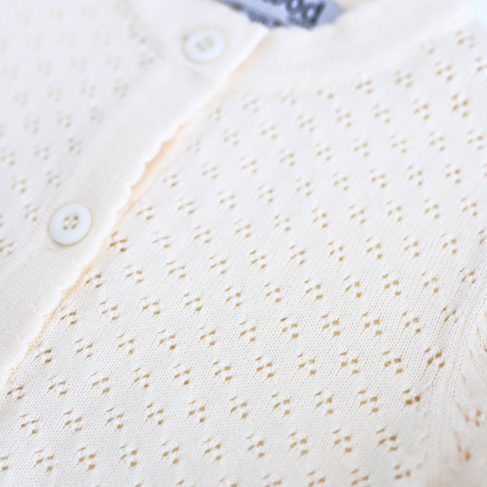 close-up of pointelle knit pattern on cream sweater with buttons