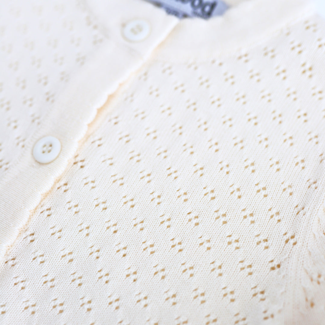 close-up of pointelle knit pattern on cream sweater with buttons