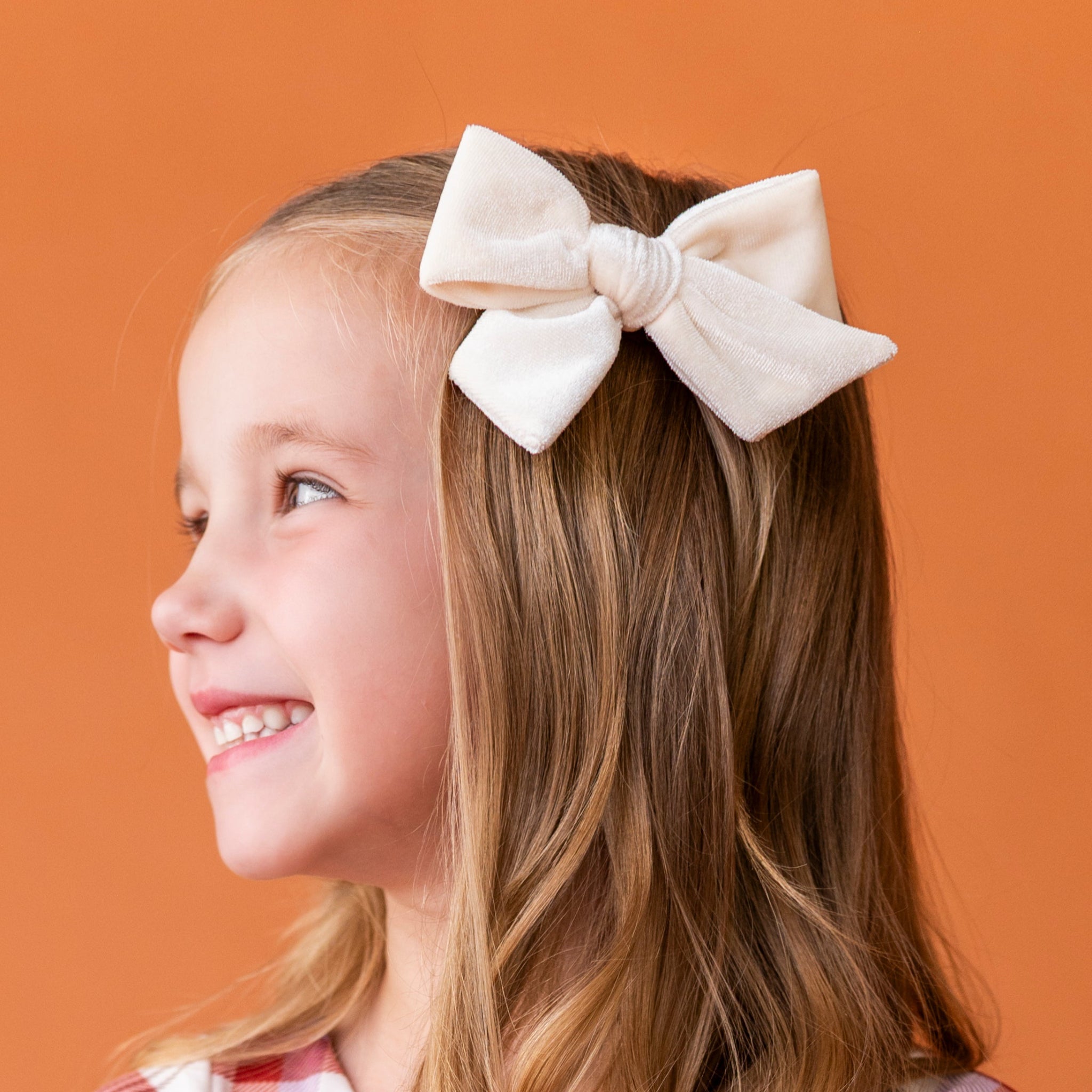 young girl with ivory velvet hair bow on alligator clip paired with fall plaid twirl dress
