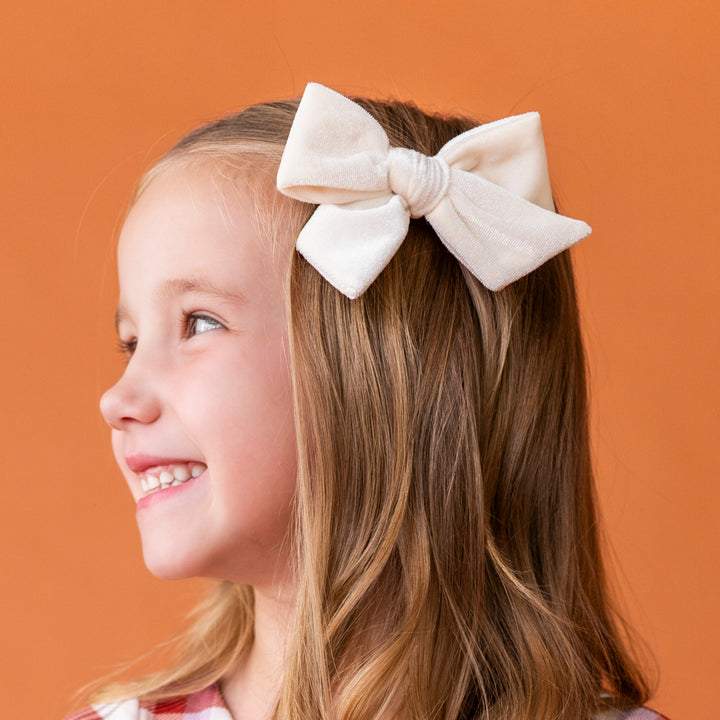young girl with ivory velvet hair bow on alligator clip paired with fall plaid twirl dress