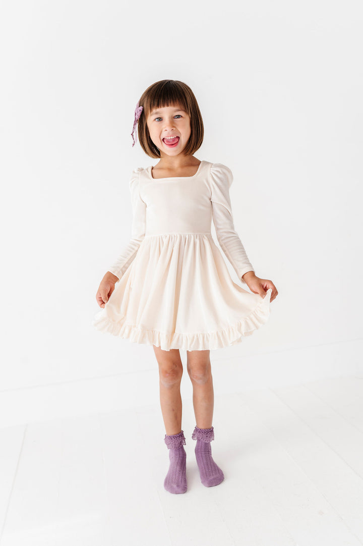 little girl wearing ivory velvet long sleeve dress with purple lace bobby socks
