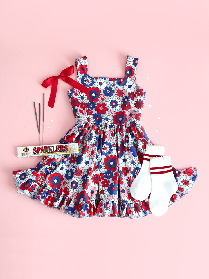 flatlay of girls floral 4th of july summer twirl dress with red striped socks and matching red satin bow
