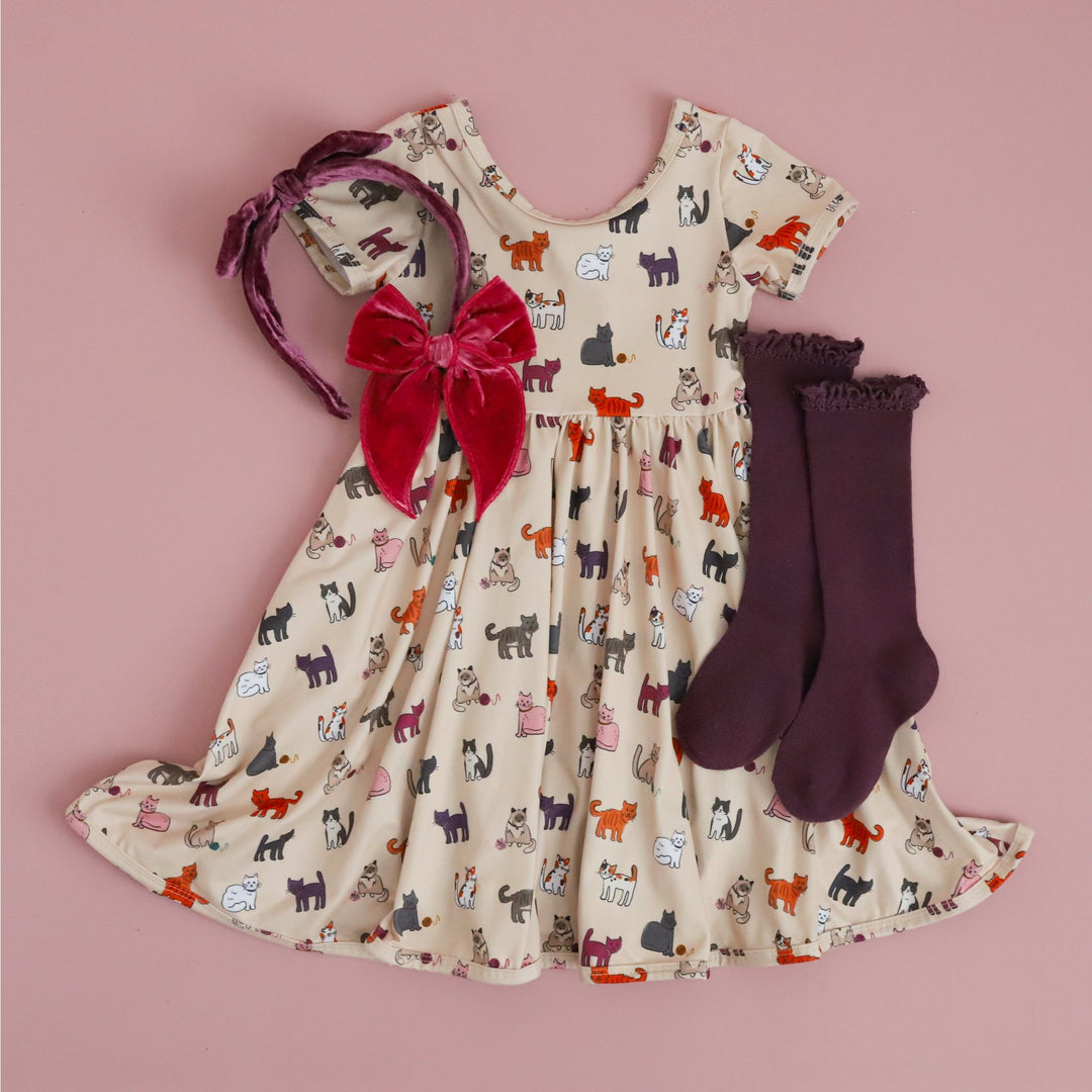 girls cream cat print dress styled with purple and fall pink knee highs and velvet hair accessories