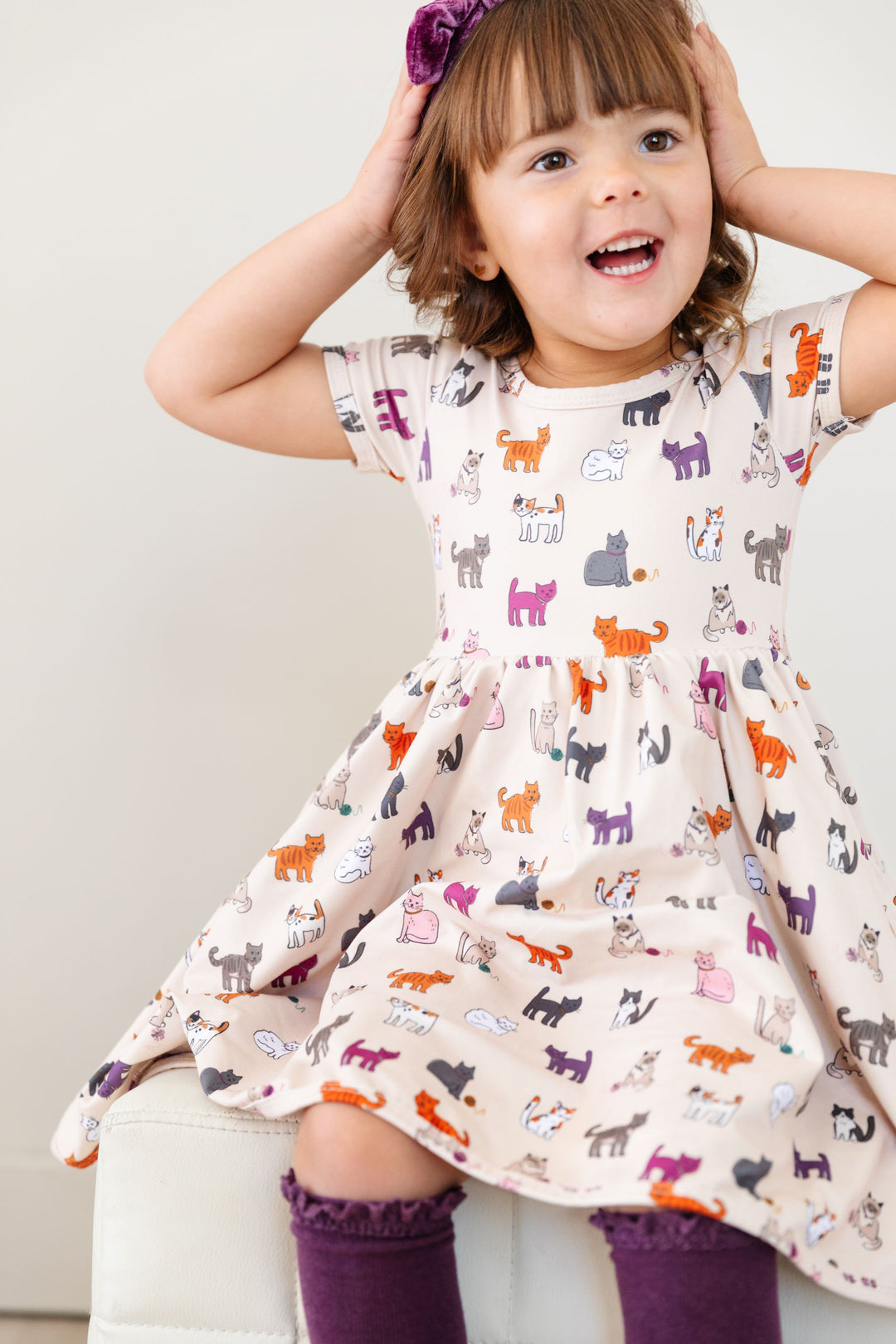 little girl in fall cat print twirl dress with matching purple knee highs and headband