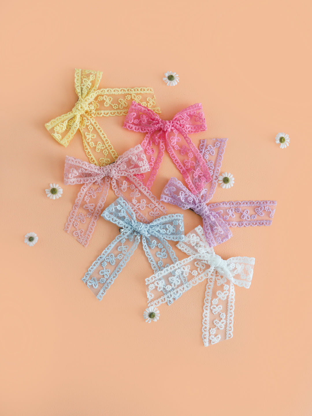 flatlay of six lace hair bows on clips in spring pastel colors 