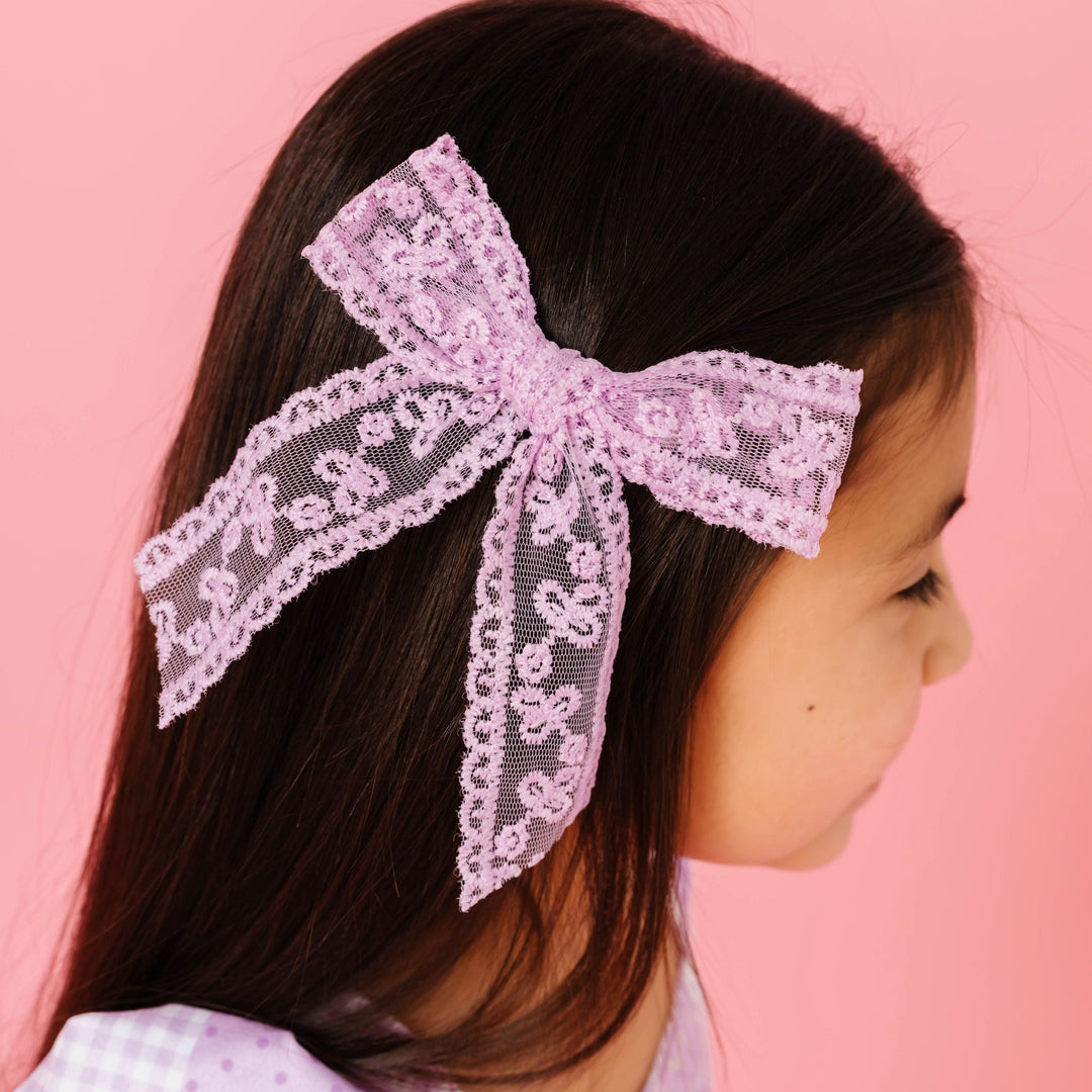 young girl wearing purple lace hair bow on alligator clip to match purple dress