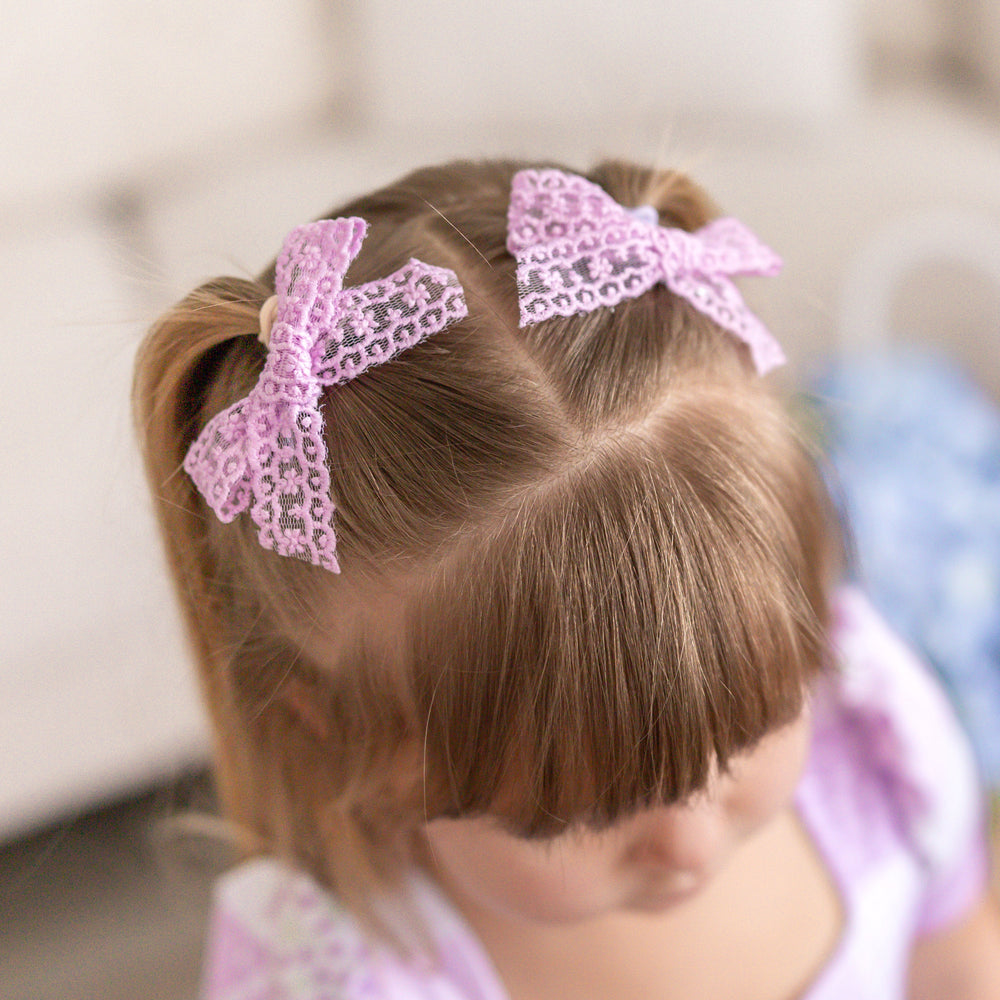 little girl in lavender lace pigtail bows on clips paired with lavender floral spring dress