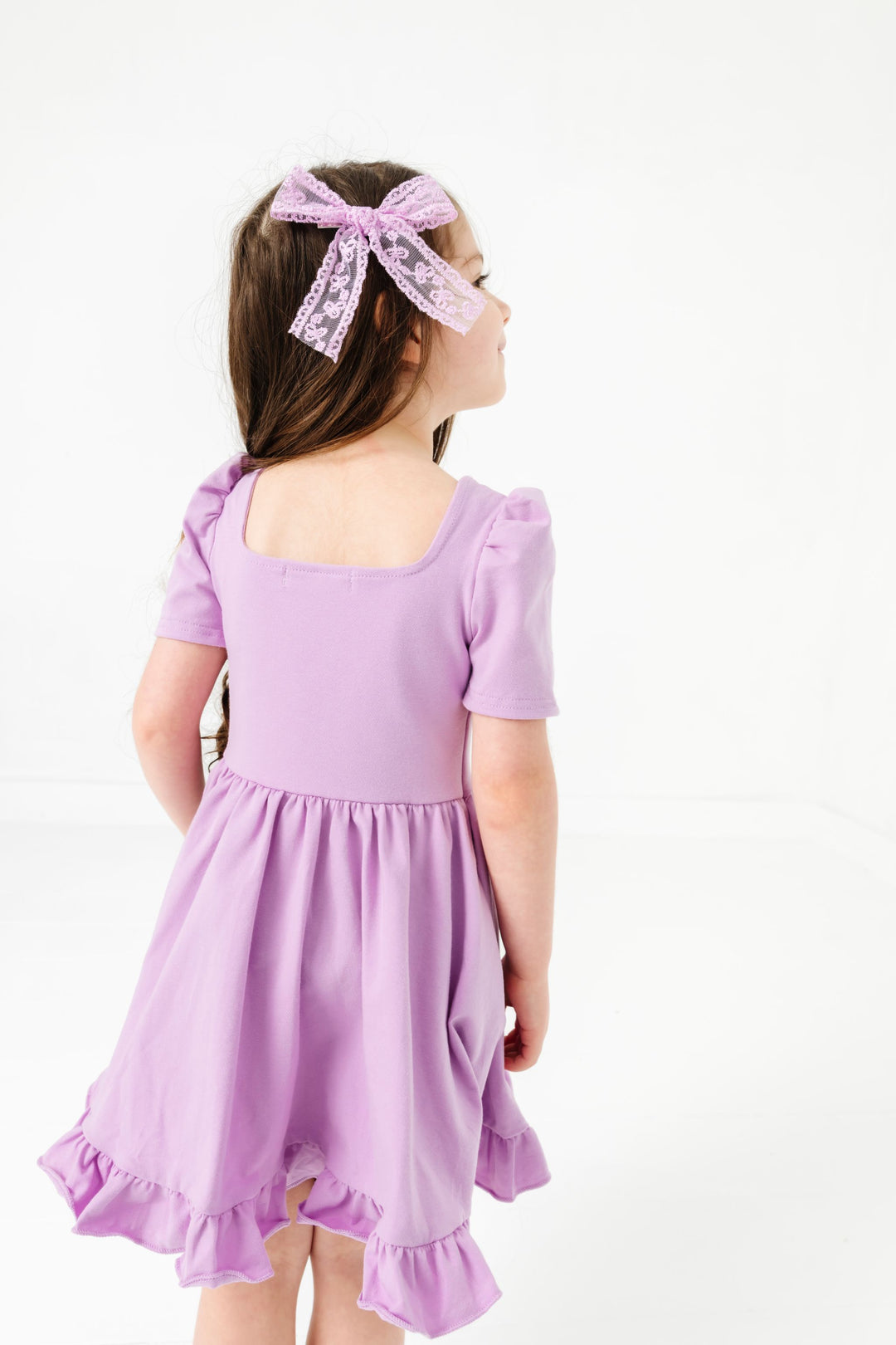 young girl in square neck short sleeve solid lavender twirl dress paired with matching lace hair bow on clip