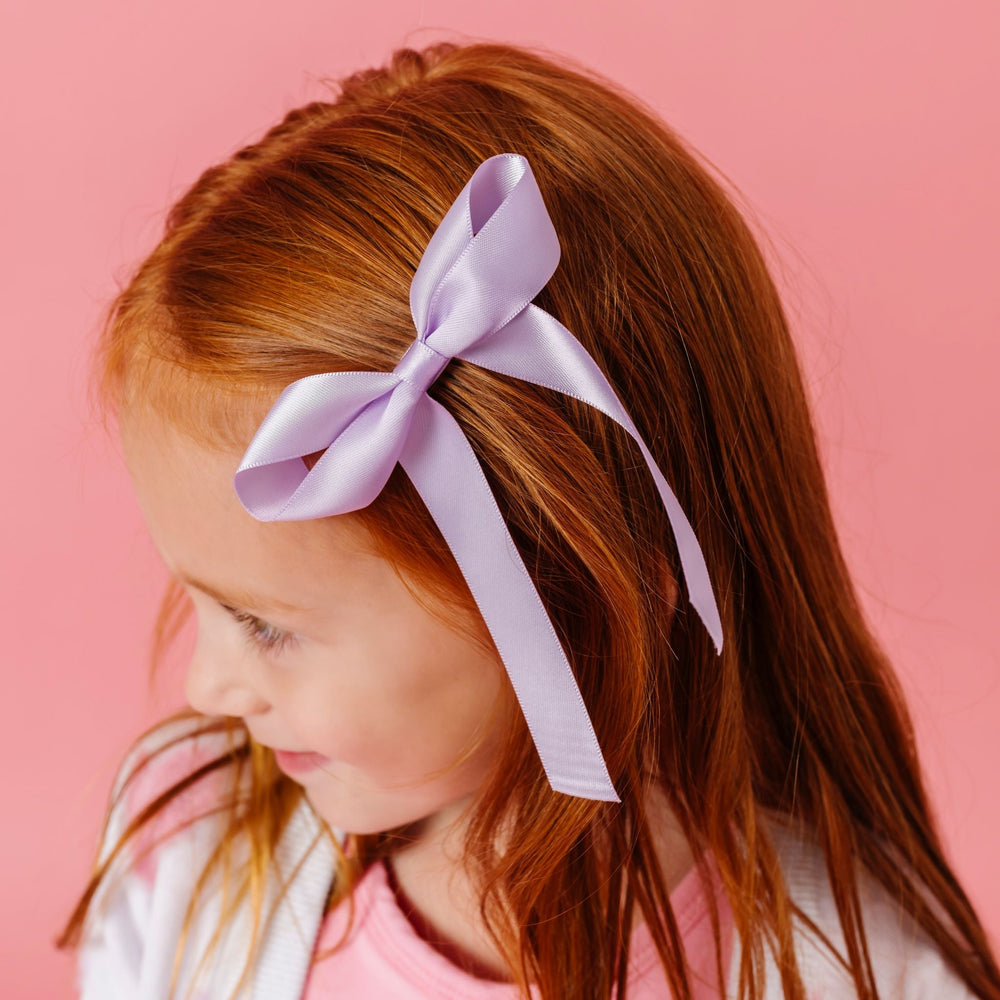little girl wearing light purple satin ribbon bow on alligator clip for spring and valentines day