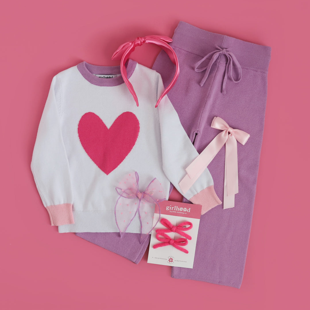 little girls styled flatlay for Darling heart sweater, lavender cotton knit sweater pants and variety of matching pink bows and headbands 