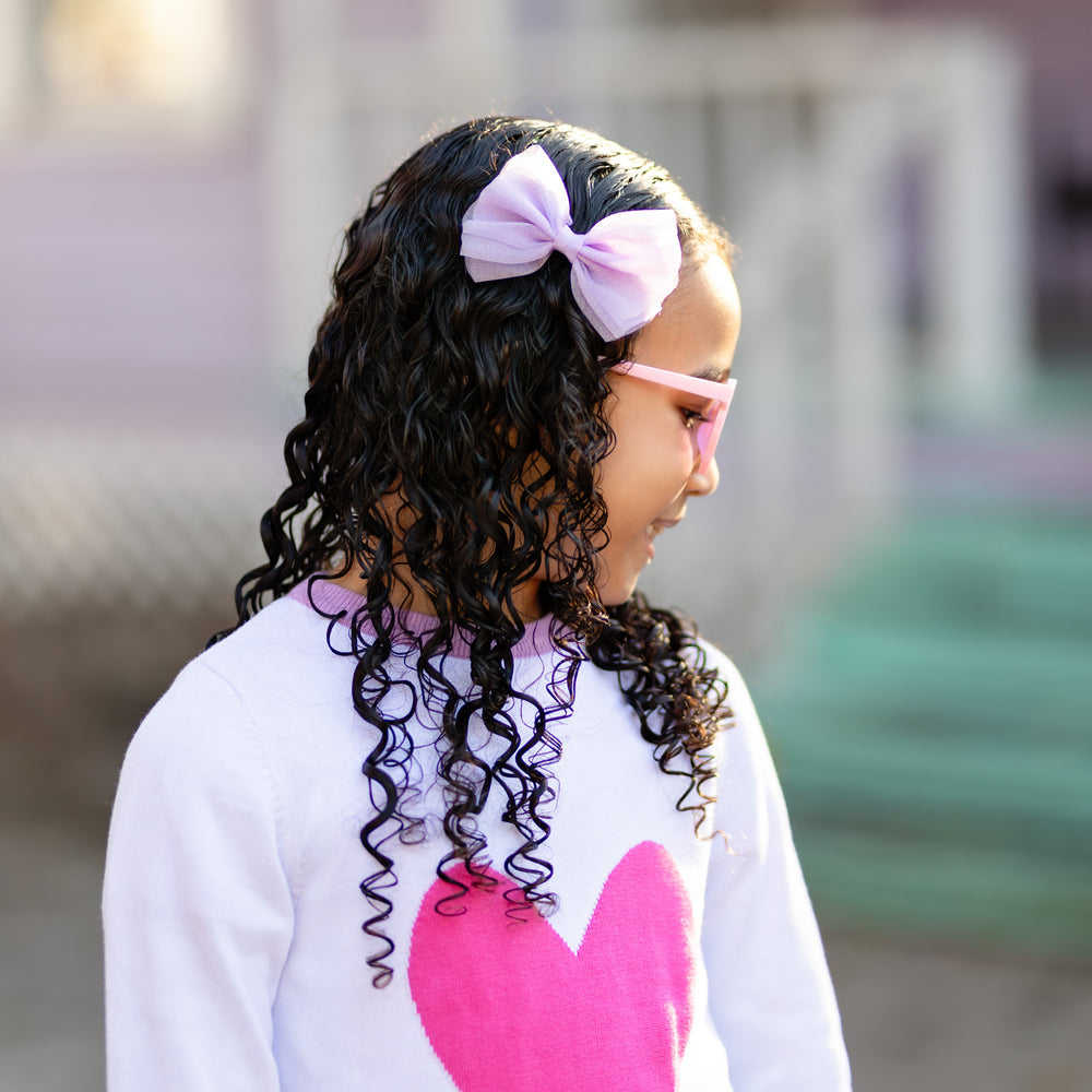 little girl with lavender tutu bow and matching Valentine's sweater with pink heart