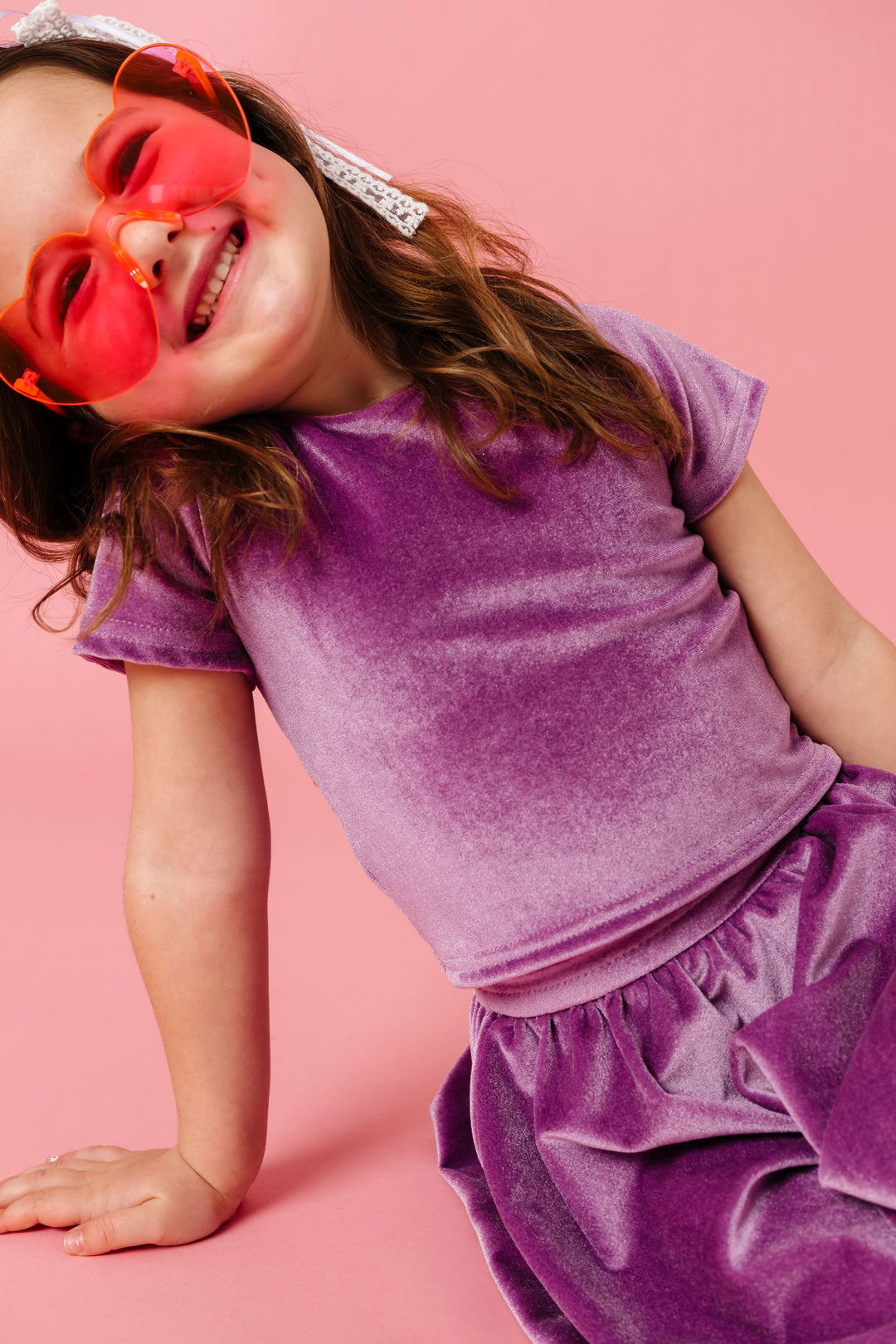 young girl sirtting with heart sunnies and lavender velvet fitted top and skort set 