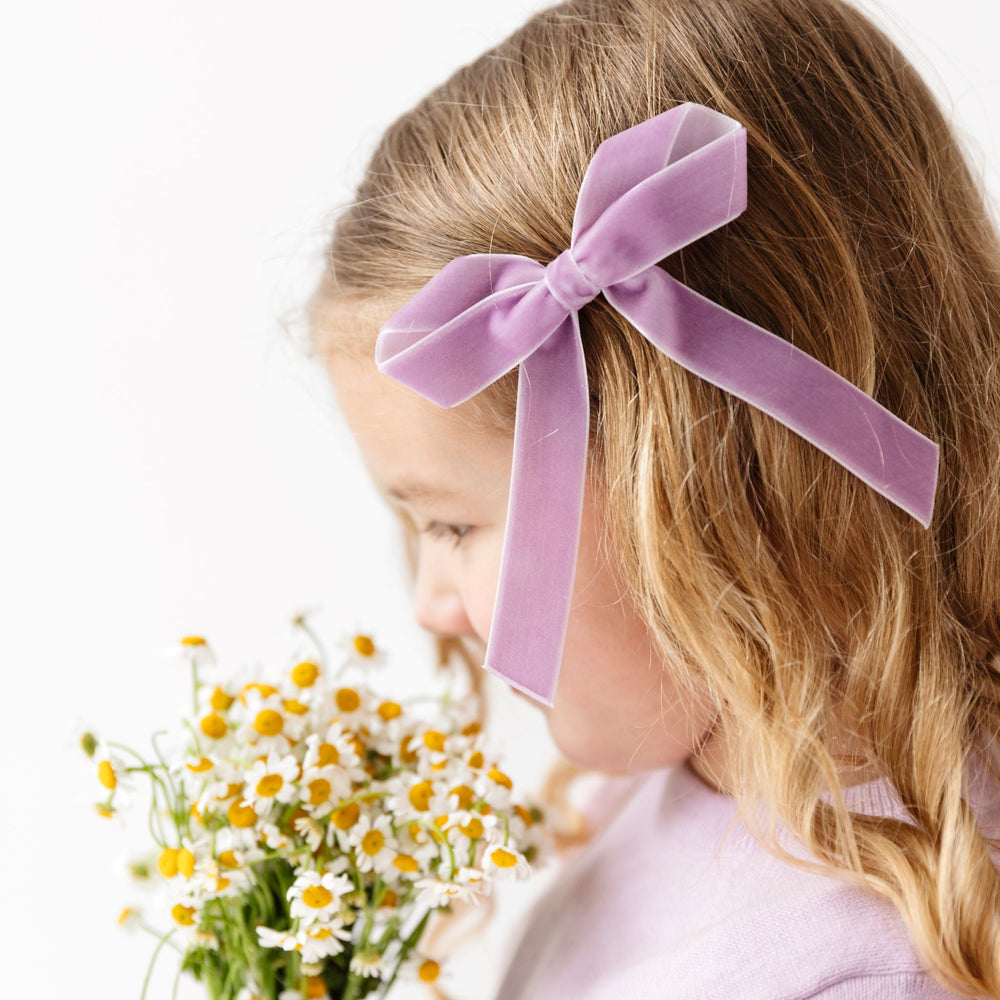 little girl holding spring flowers with pastel purple velvet ribbon bow on clip