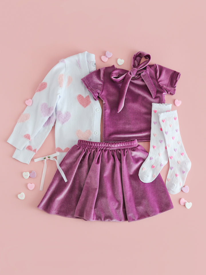 girls fitted lavender velvet top with bow back and matching velvet skort styled for conversation heart vibes with pastel heart sweater and knee socks