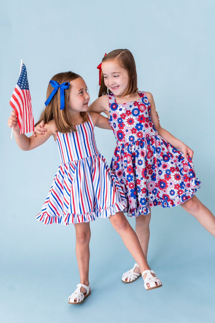 sisters in coordinating red, white and blue stripe and floral twirl dresses for the fourth of july