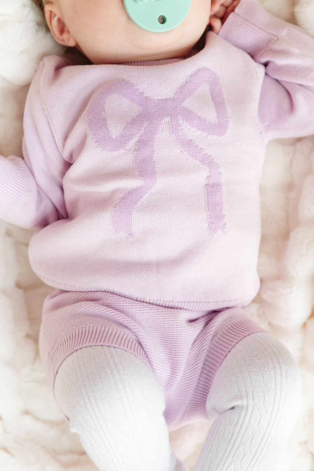 baby girl in lilac sweater with purple bow and matching lilac knit bloomers