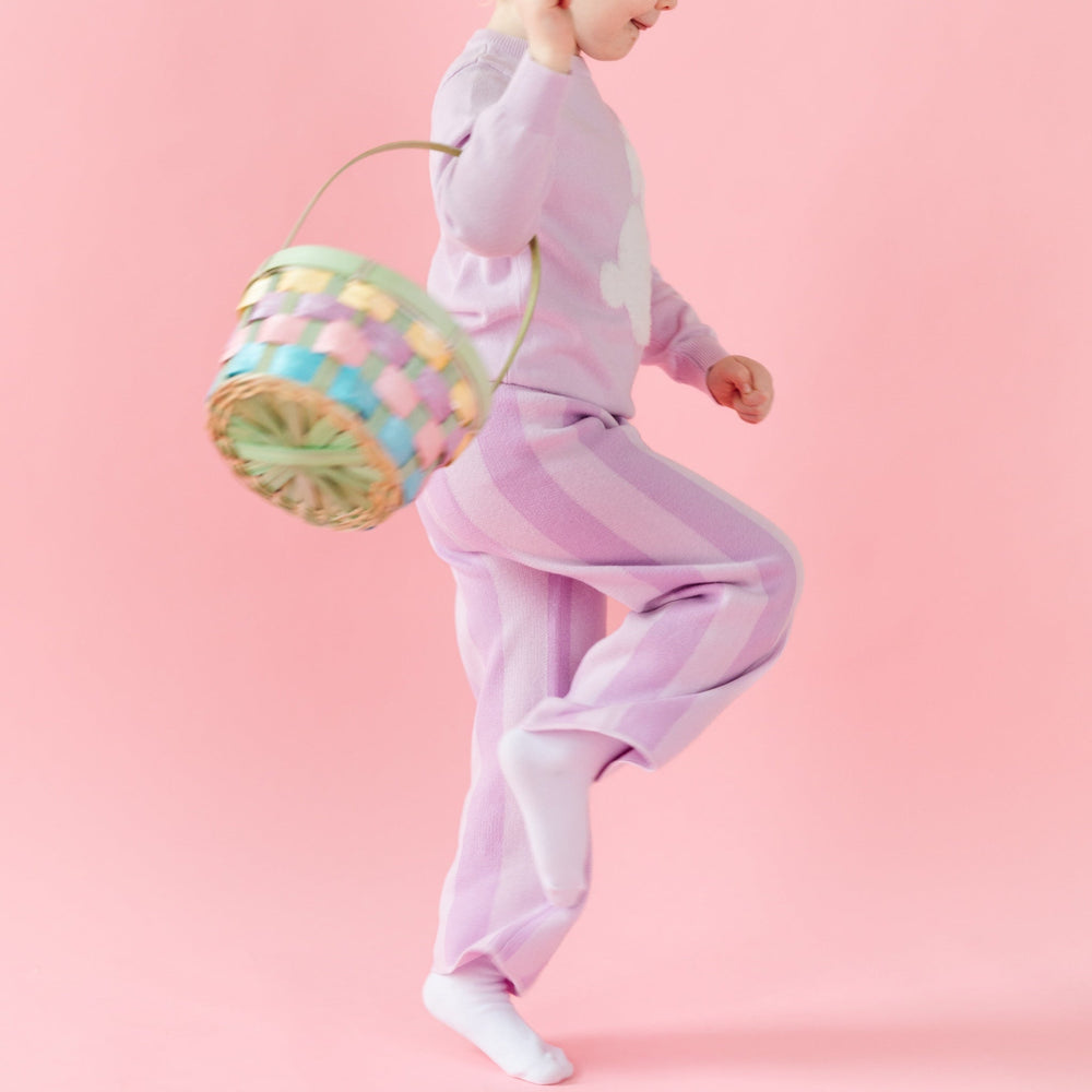 girl skipping with easter basket in lilac purple striped cotton knit pants and matching bunny sweater