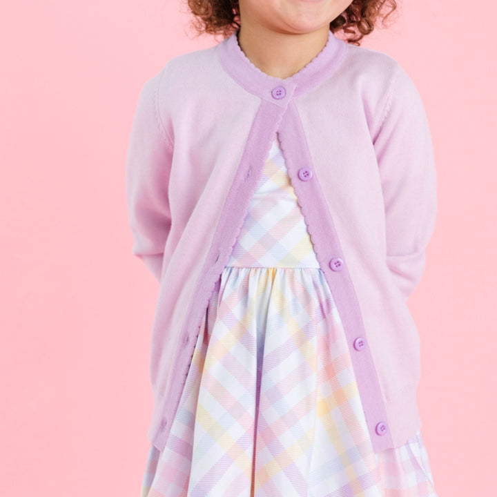 little girl in pastel gingham twirl dress and matching lilac and lavender button front cardigan