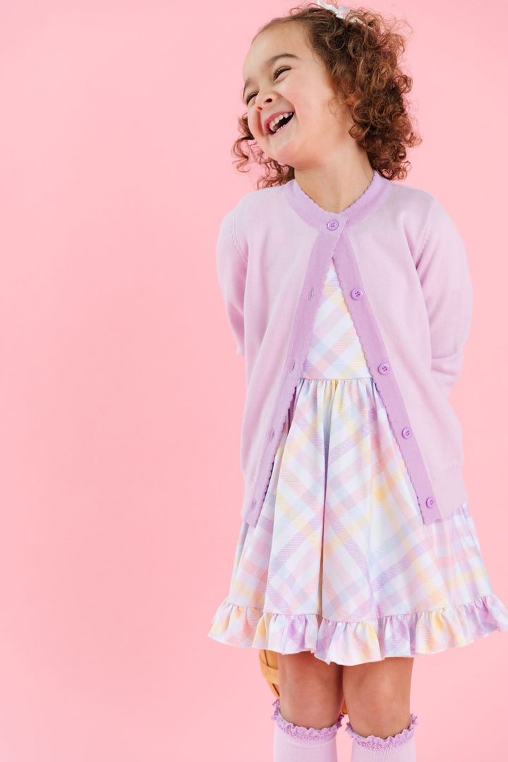 little girl in springy pastel gingham twirl dress and matching two tone purple cardigan and knee highs