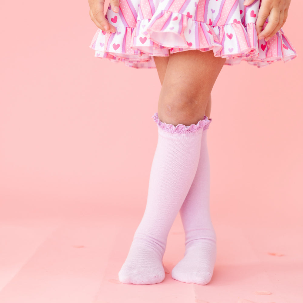 closeup of pastel purple lace top knee high socks paired with pink wallpaper inspired print dress